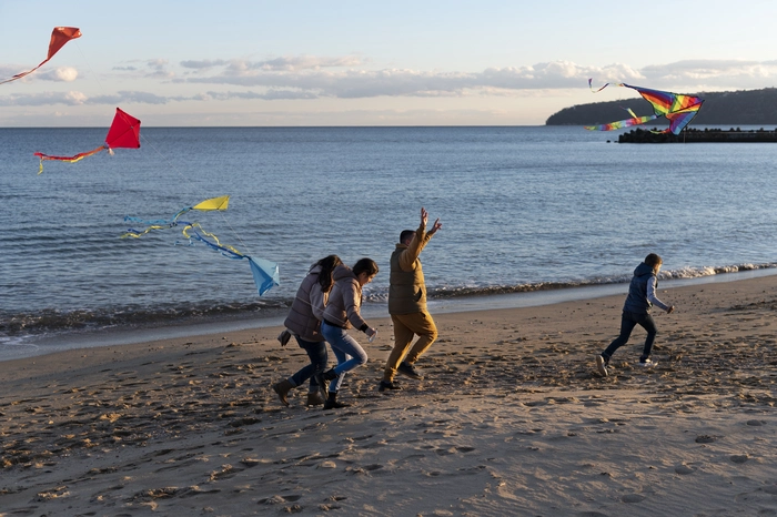Une famille profitant de la plage en hors saison pour s'adonner au cerf volant